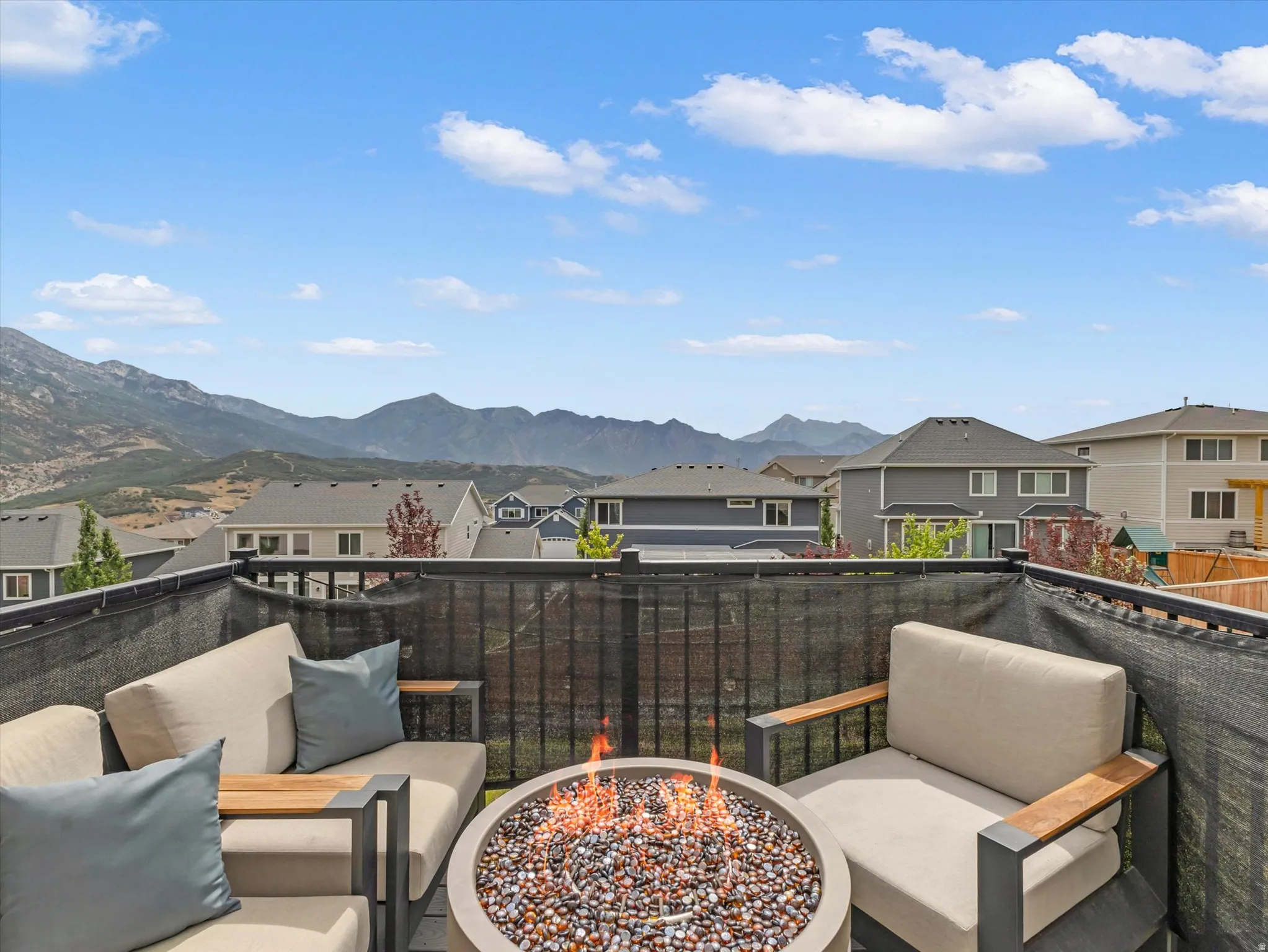 Outdoor patio featuring a built-in fire pit with decorative stones and a mountain backdrop