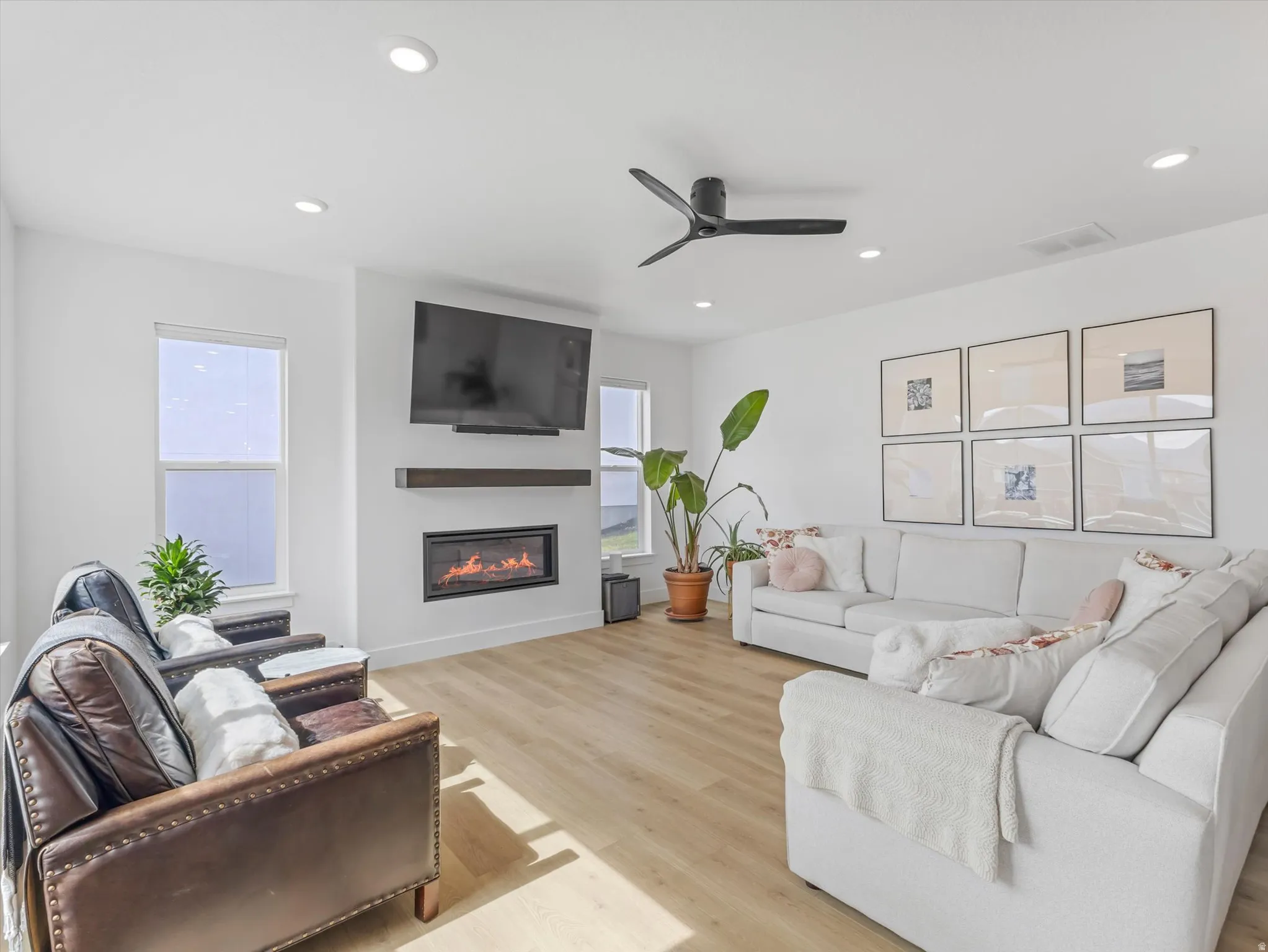 Spacious living area featuring light wood-finish flooring, recessed lighting, and a contemporary ceiling fan