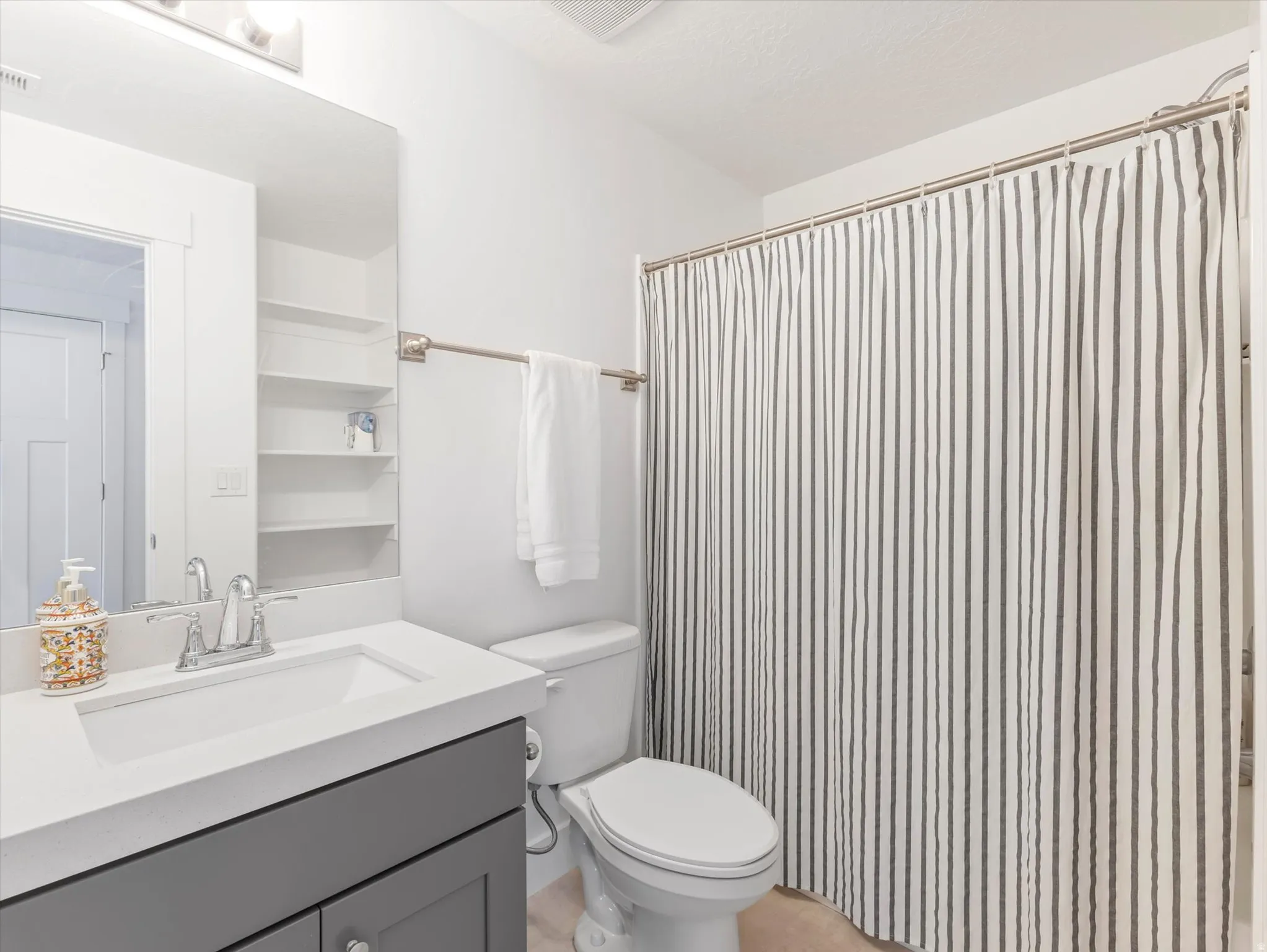 Bathroom featuring a gray vanity with an integrated sink, polished chrome faucet, and white countertop