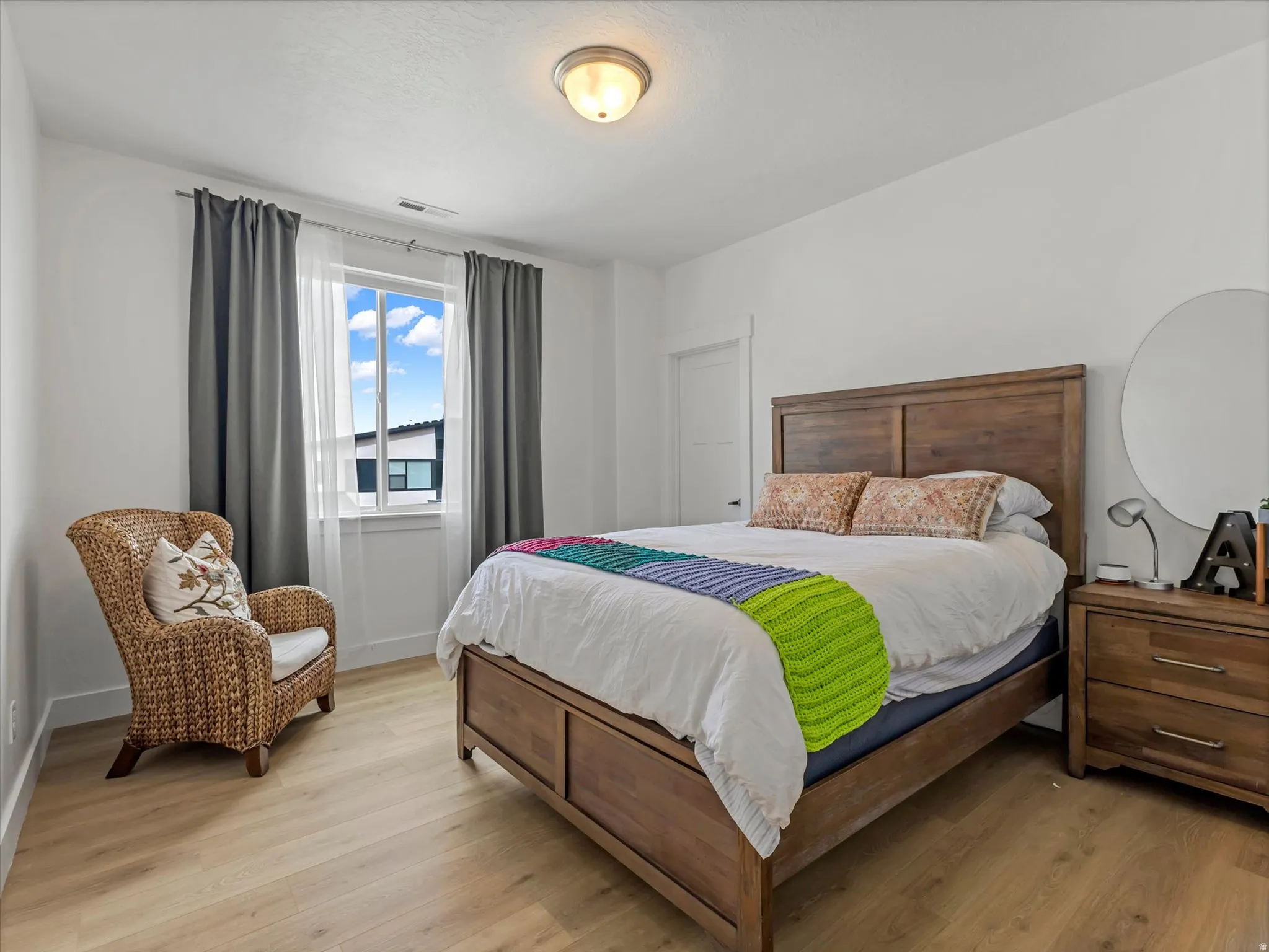 Bright bedroom featuring light wood-finish flooring and white walls