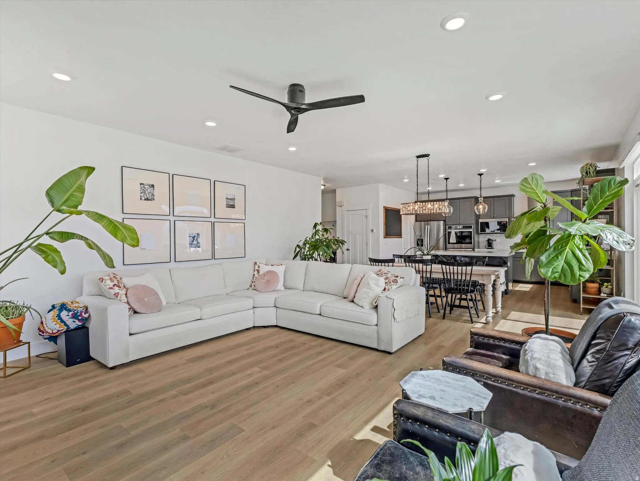 Open-concept living area with wood-finish flooring, recessed lighting, and a modern ceiling fan