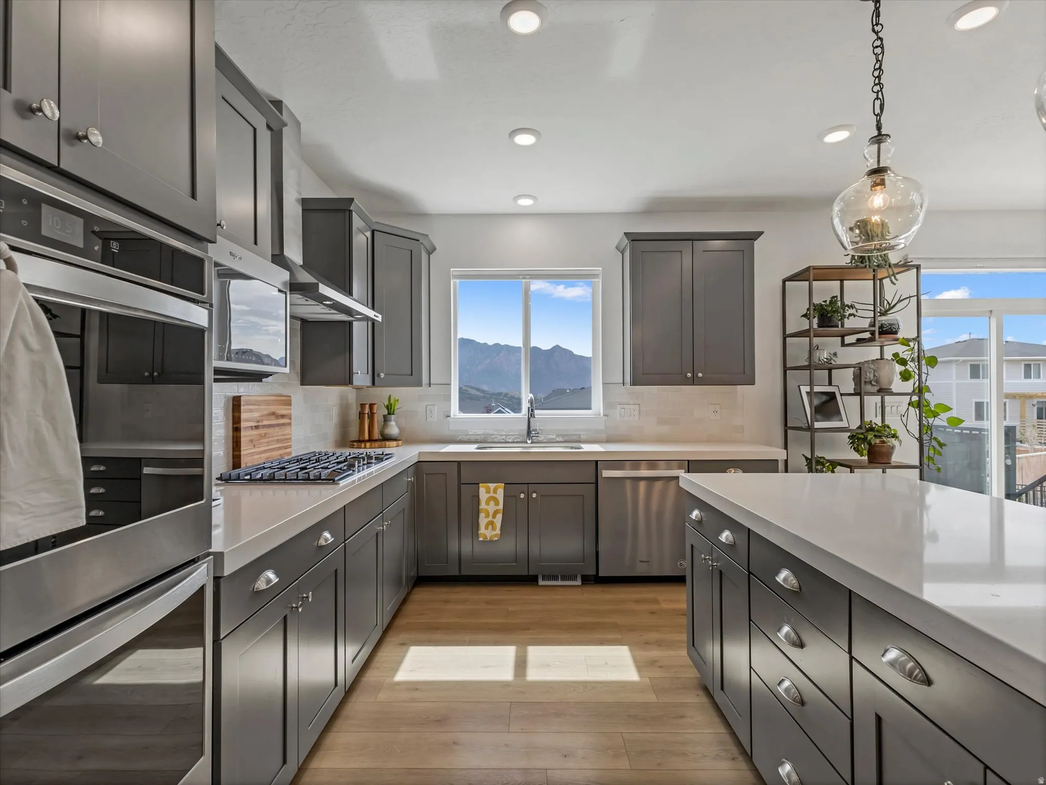 Kitchen featuring gray shaker cabinetry, stainless steel appliances, a gas range, white countertops, and wood-finish flooring