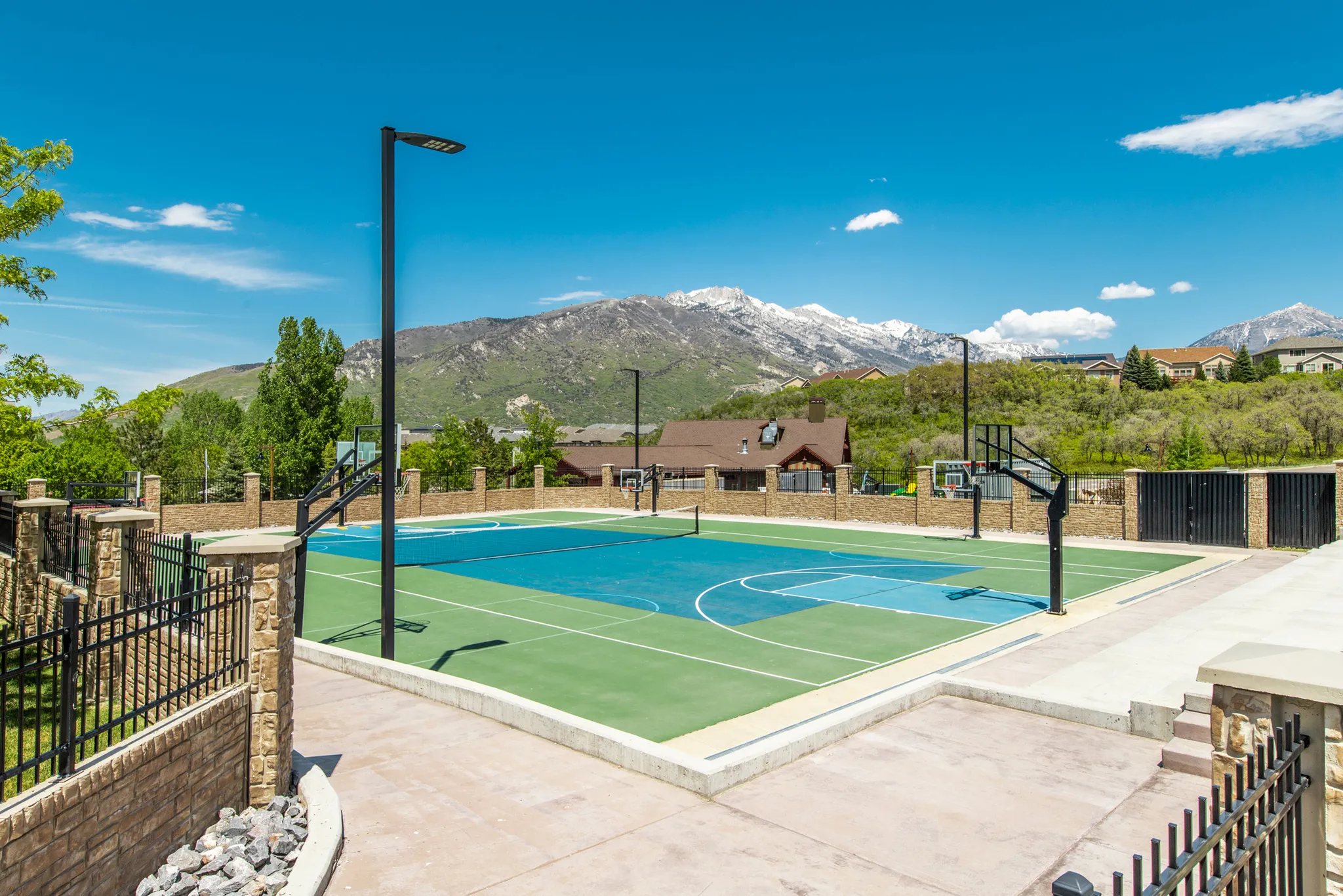 Multi-sport court featuring a vibrant blue and green surface, basketball hoops, and tennis net