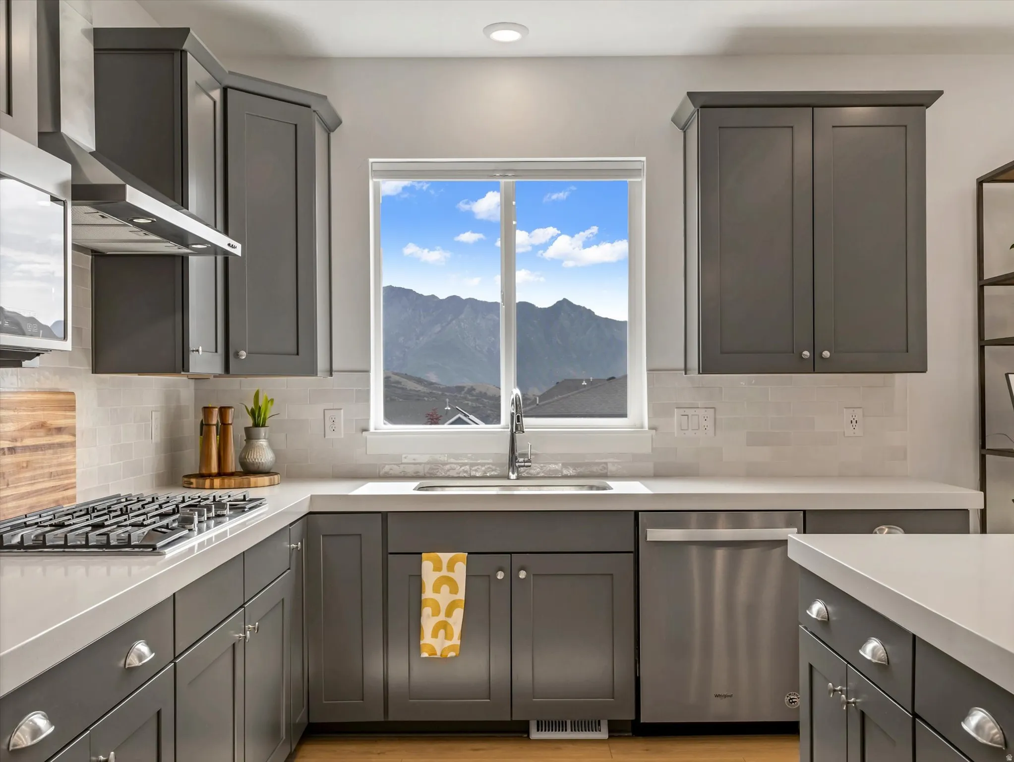 Kitchen featuring a gas range, stainless steel appliances, a white subway tile backsplash, light countertops, and dark shaker-style cabinetry