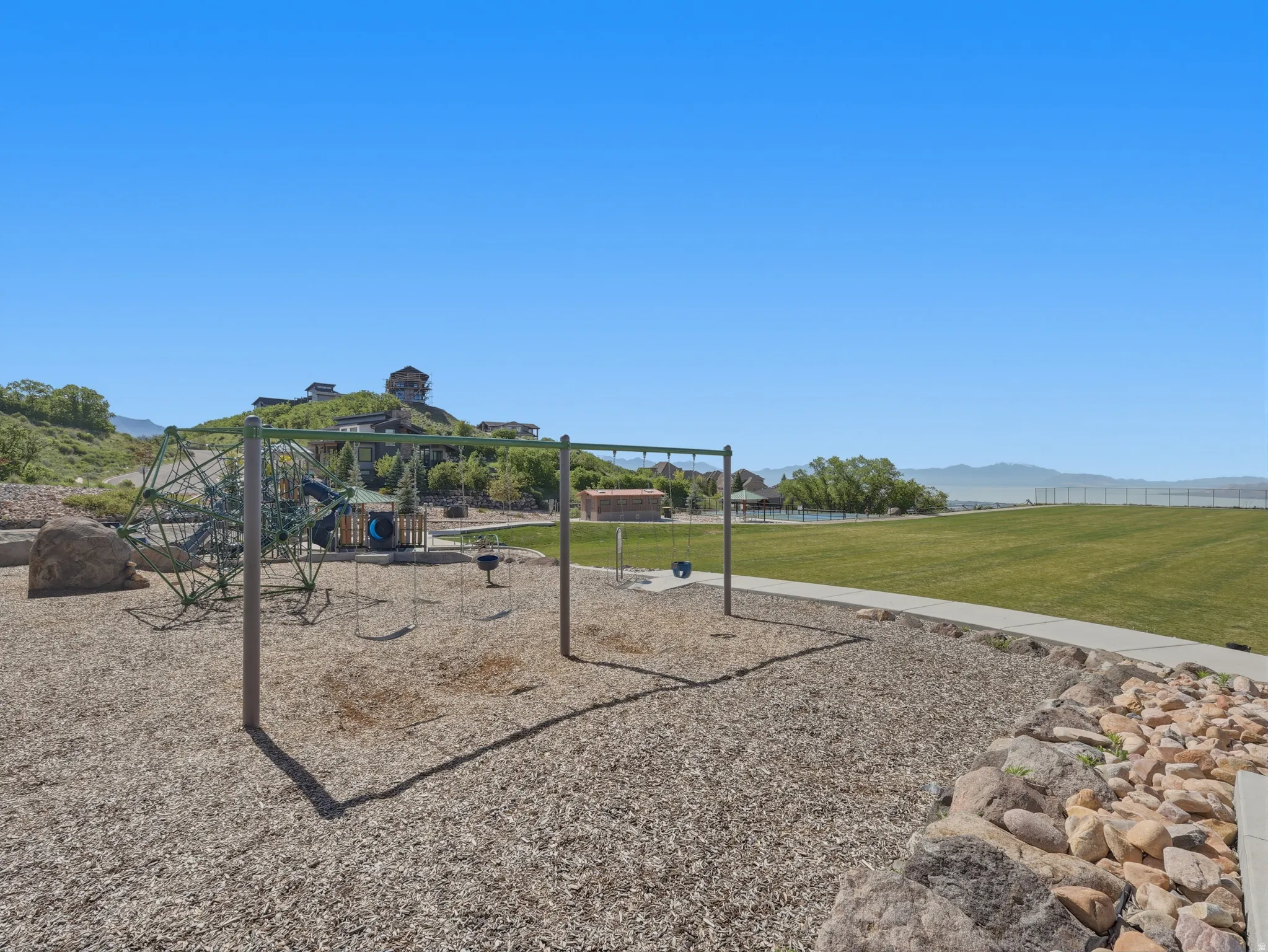 Community playground featuring swings and climbing structures on wood chip surfacing