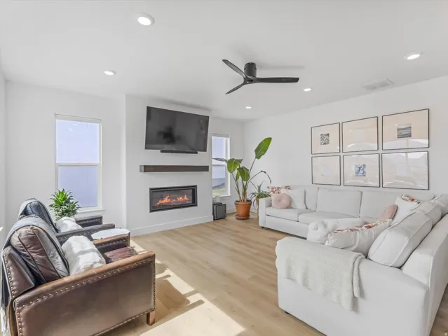 Spacious living area featuring light wood-finish flooring, recessed lighting, and a contemporary ceiling fan