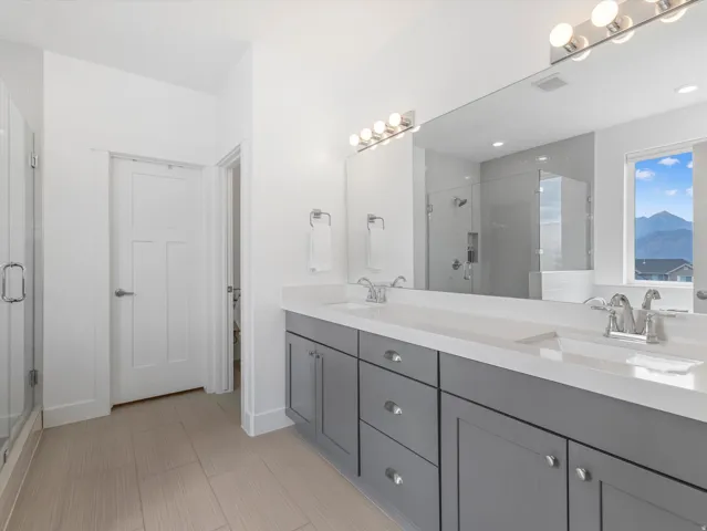 Bathroom featuring a double vanity with gray cabinetry, white countertops, and chrome fixtures