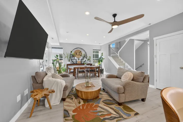 Open-concept living area featuring light wood-finish flooring, recessed lighting, a contemporary ceiling fan, and a light gray wall color