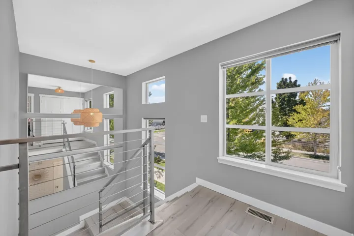 Staircase with contemporary cable railing, wood-finish flooring, and multiple windows