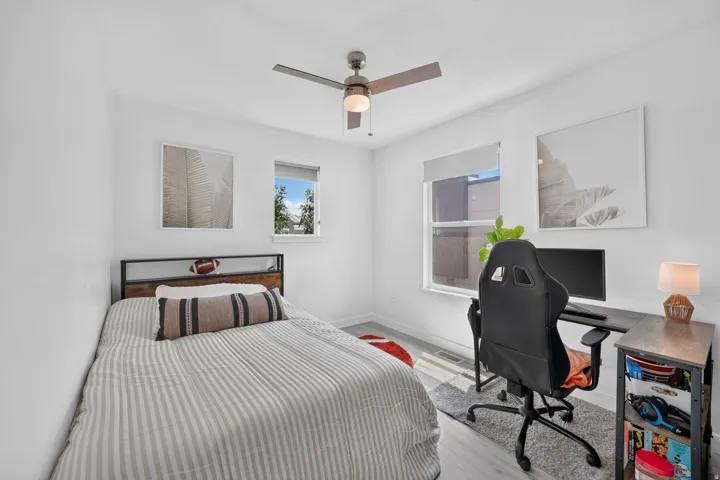 Bedroom featuring light wood-finish flooring, white painted walls, and a ceiling fan with integrated lighting