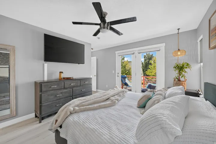 Spacious room with light gray walls, light wood-finish flooring, and a modern ceiling fan