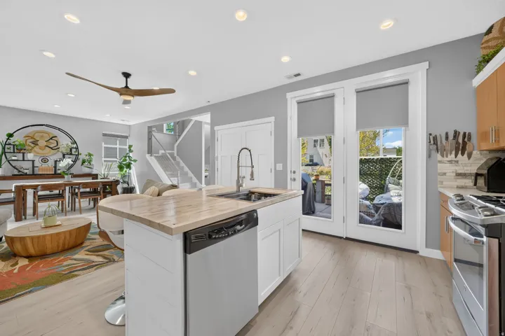 Open-concept kitchen and living area featuring light wood-finish flooring, recessed lighting, and a modern ceiling fan