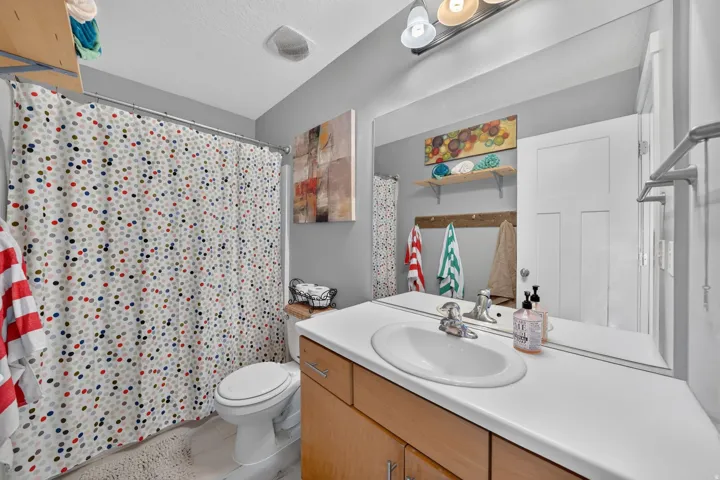 Bathroom featuring a wood-finish vanity with a white countertop and an integrated sink, a large mirror, and a wall-mounted light fixture