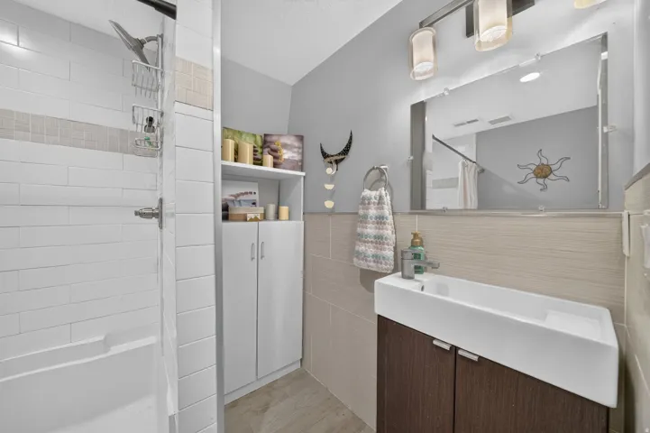 Contemporary bathroom featuring a sleek wall-mounted sink with dark wood-finish cabinetry