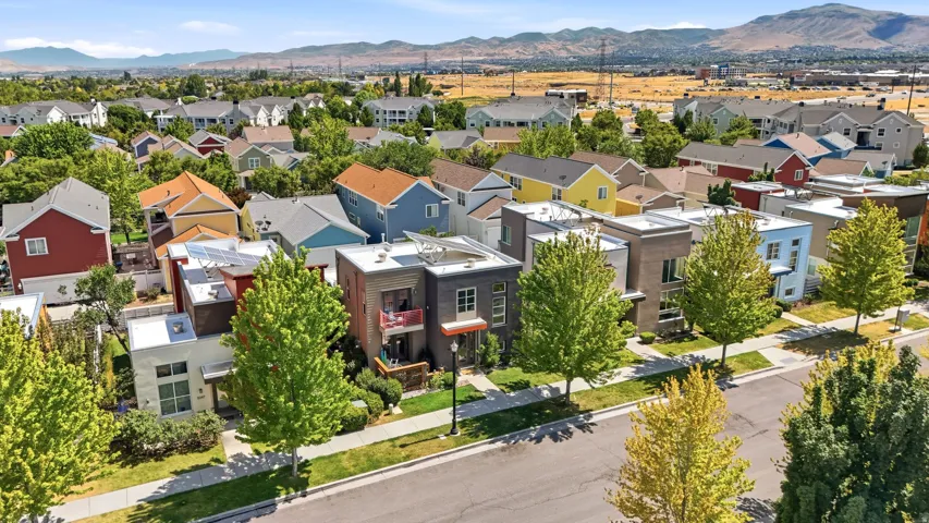 Modern residential street featuring a variety of architectural styles, mature street trees, and a mountain backdrop