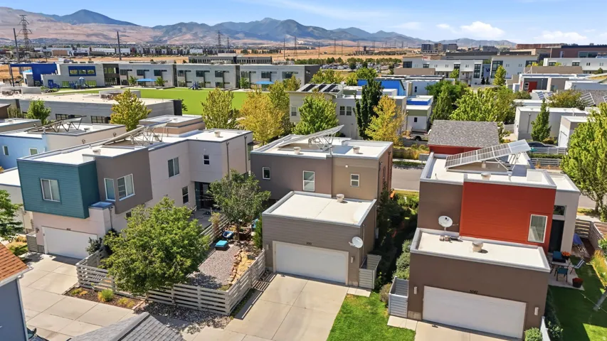 Modern residential architecture featuring flat roofs, integrated solar panels, attached garages, and a fenced patio area