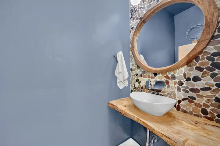 Powder room featuring a live-edge wood countertop, vessel sink, and pebble tile accent wall