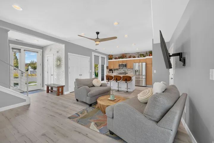 Open-concept living area with light wood-finish flooring, recessed lighting, and a contemporary ceiling fan