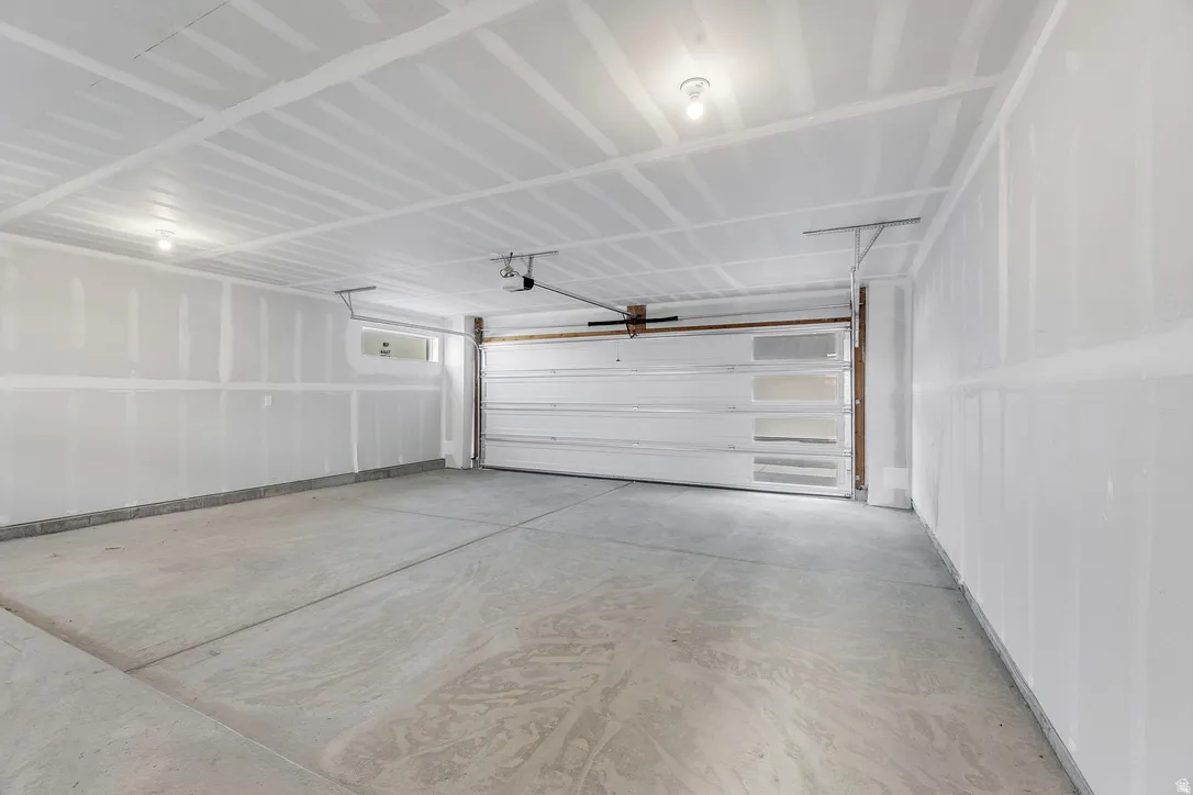 Spacious garage with concrete flooring, drywall-finished walls and ceiling, and a white overhead door