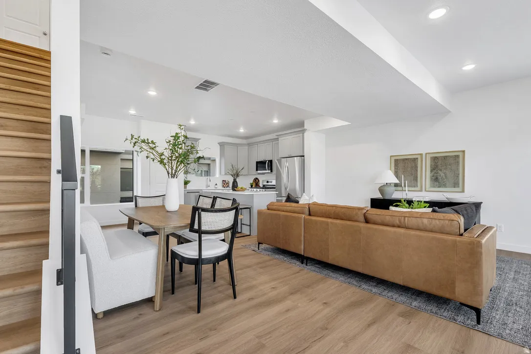 Open-concept living space featuring wood-finish flooring, recessed lighting, and a modern kitchen with light gray cabinetry and stainless steel appliances