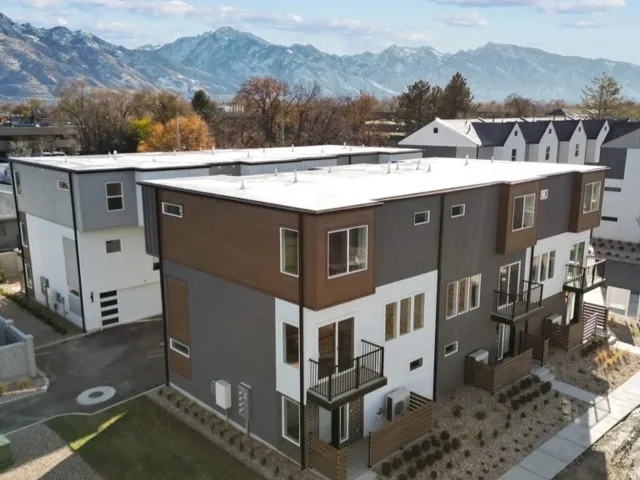 Modern multi-level exterior featuring a contemporary design with flat roofs, multiple balconies, and a distinctive grey, white, and wood-finish facade
