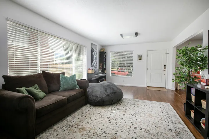 Living area featuring wood-finish flooring and loads of natural lights from large windows.