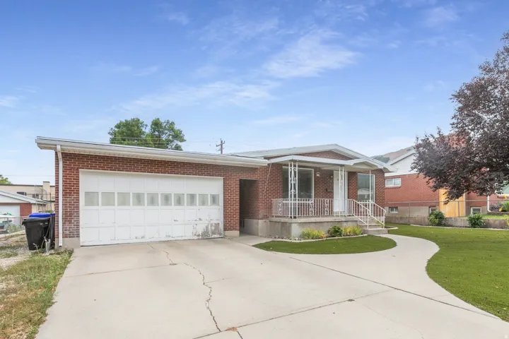 Brick exterior with an attached garage, featuring a concrete driveway and walkway
