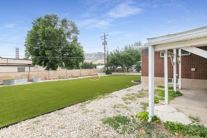 Expansive backyard featuring artificial turf, a gravel perimeter, and a chain link fence
