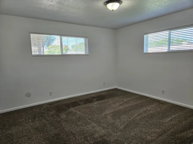 Neutral-toned wall-to-wall carpeting complements the white baseboards and walls