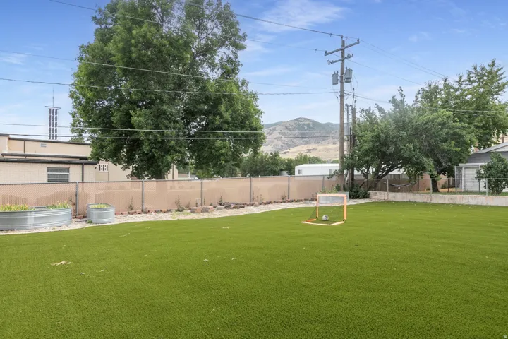 Expansive green artificial turf lawn bordered by a chain-link fence with privacy screening