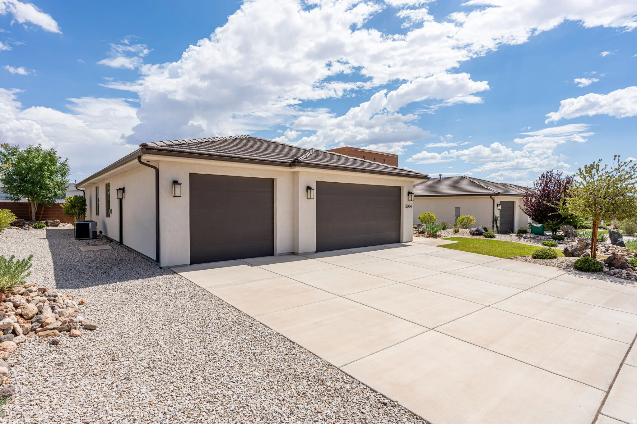 Stucco exterior with two dark garage doors and complementary exterior light fixtures