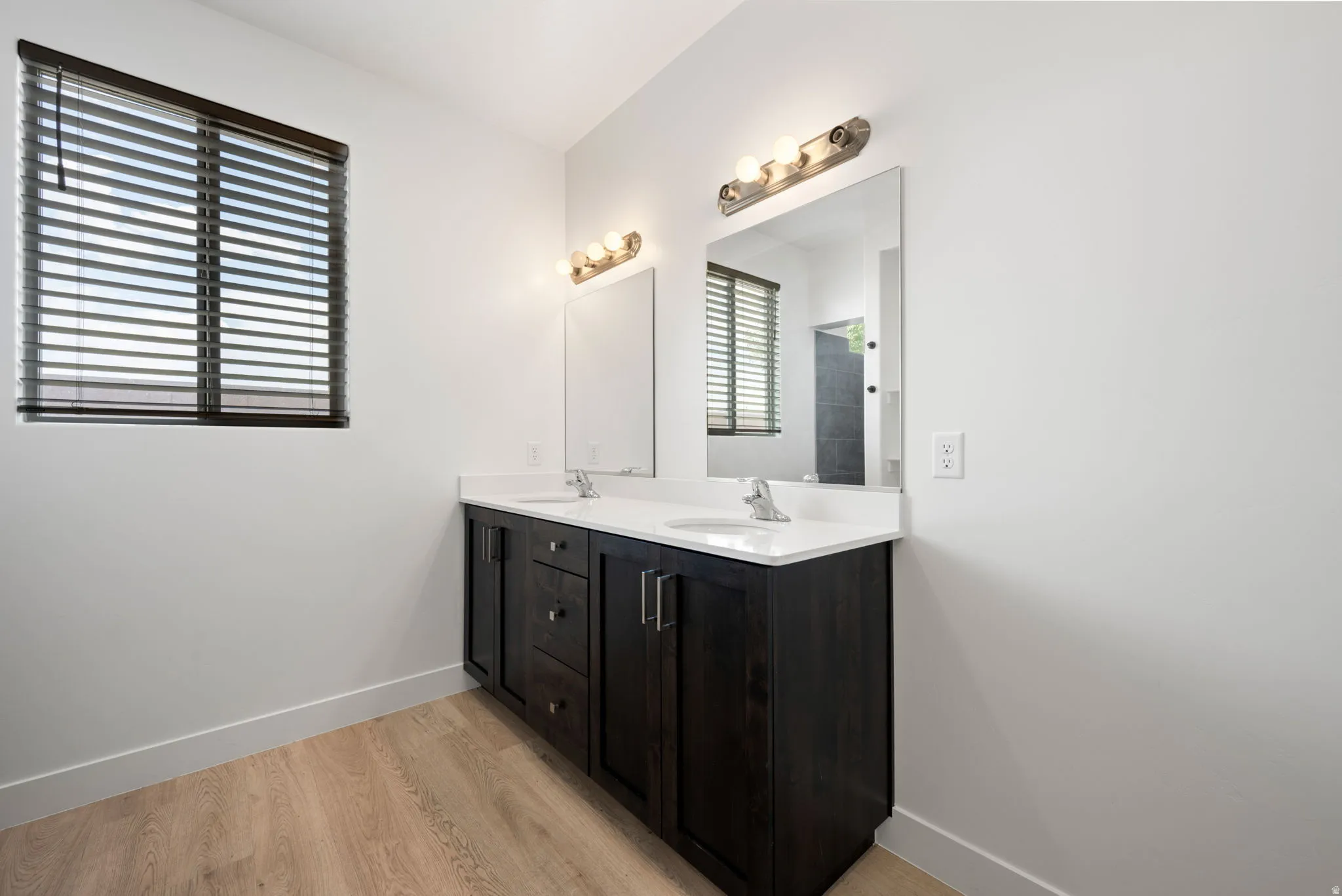 Double vanity featuring dark wood-finish cabinetry, white countertops, and dual undermount sinks