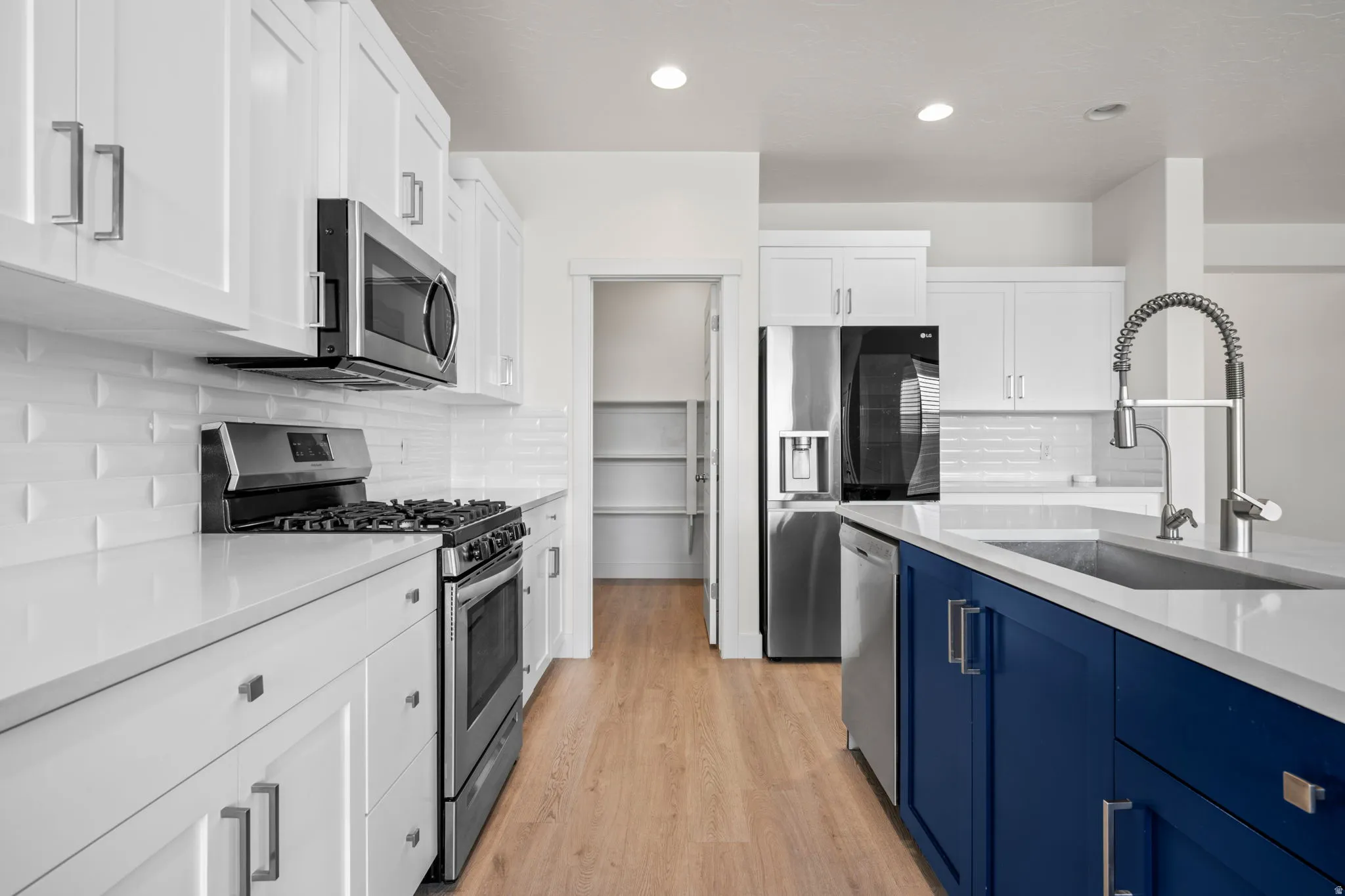 Modern kitchen featuring a blue island with an undermount sink and gooseneck faucet