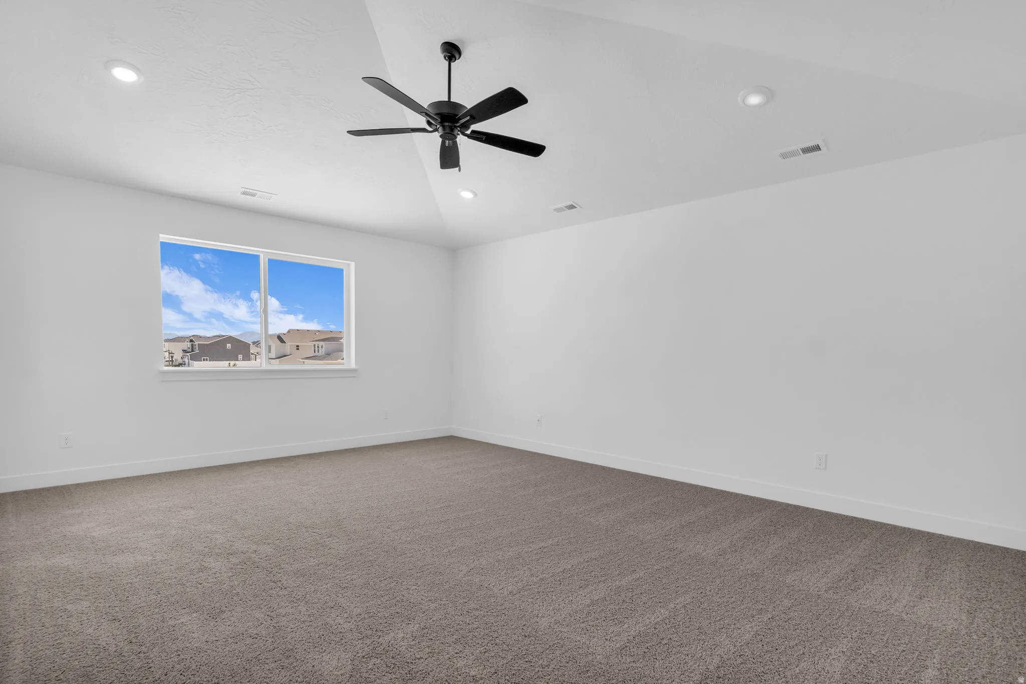 Spacious primary bedroom with vaulted ceiling and ceiling fan adjacent to primary suite including a large walk-in closet.