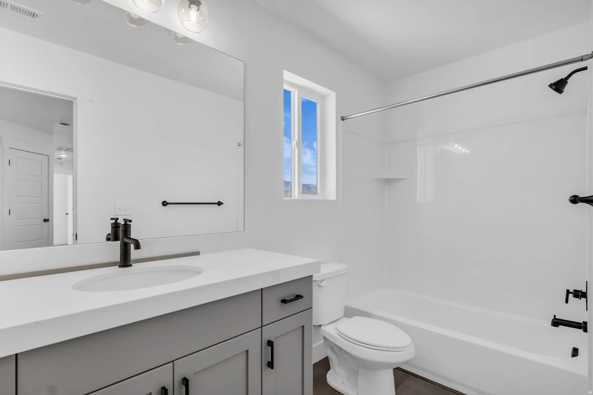 Full secondary bath with painted wood cabinets and quartz slab countertops.