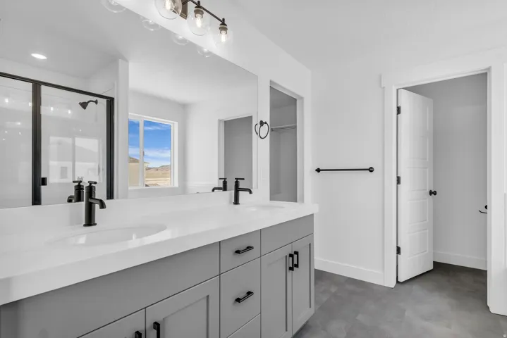 Primary bath as part of primary suite with dual sinks, painted wood cabinets and quartz slab countertops.
