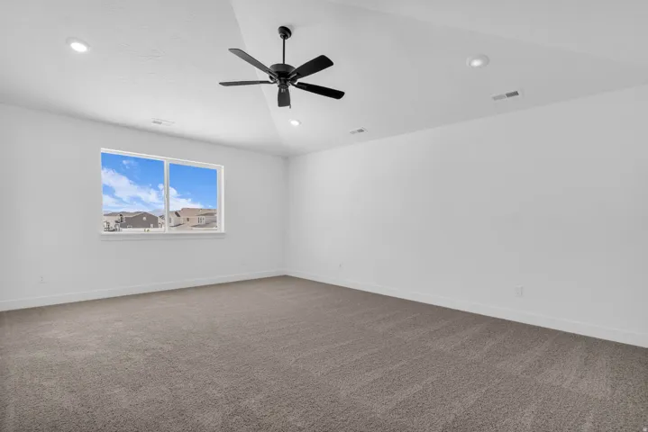 Spacious primary bedroom with vaulted ceiling and ceiling fan adjacent to primary suite including a large walk-in closet.