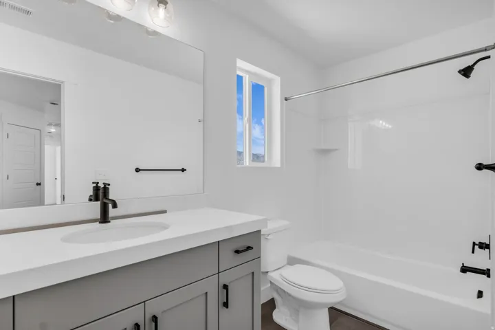 Full secondary bath with painted wood cabinets and quartz slab countertops.