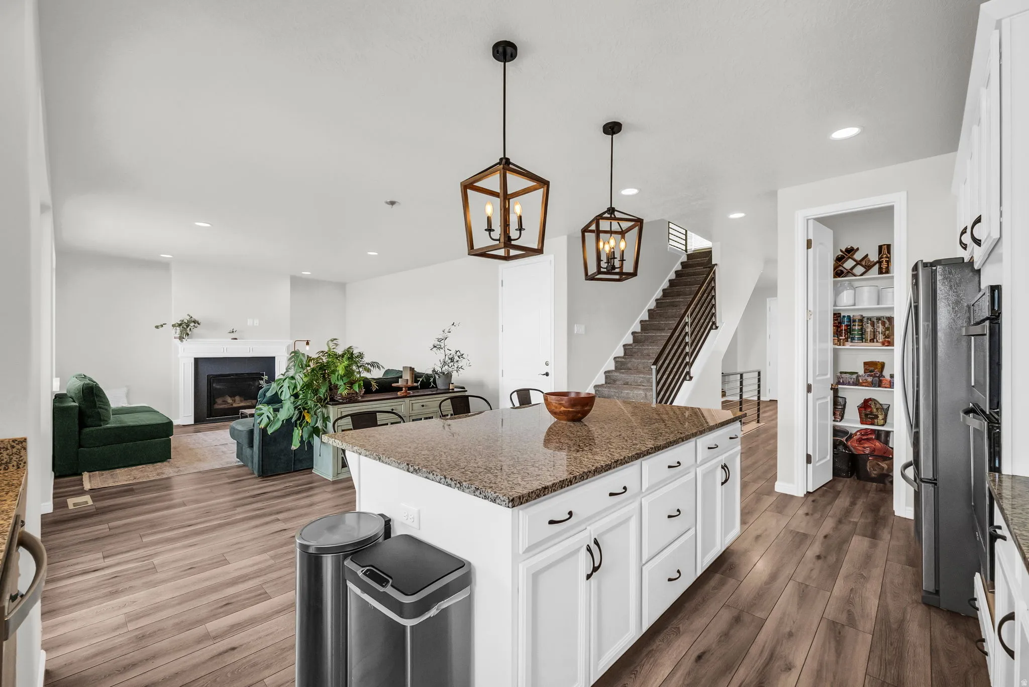 Kitchen island featuring a granite countertop, white cabinetry with dark hardware, and two pendant light fixtures