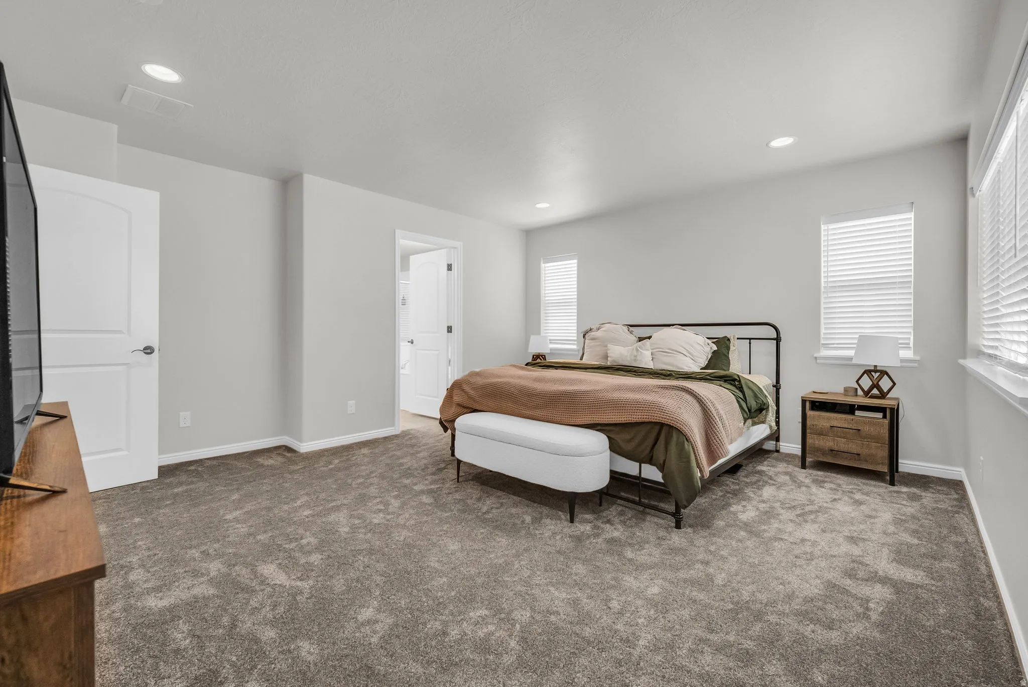 Spacious carpeted room featuring multiple windows with blinds, recessed ceiling lighting, and crisp white trim