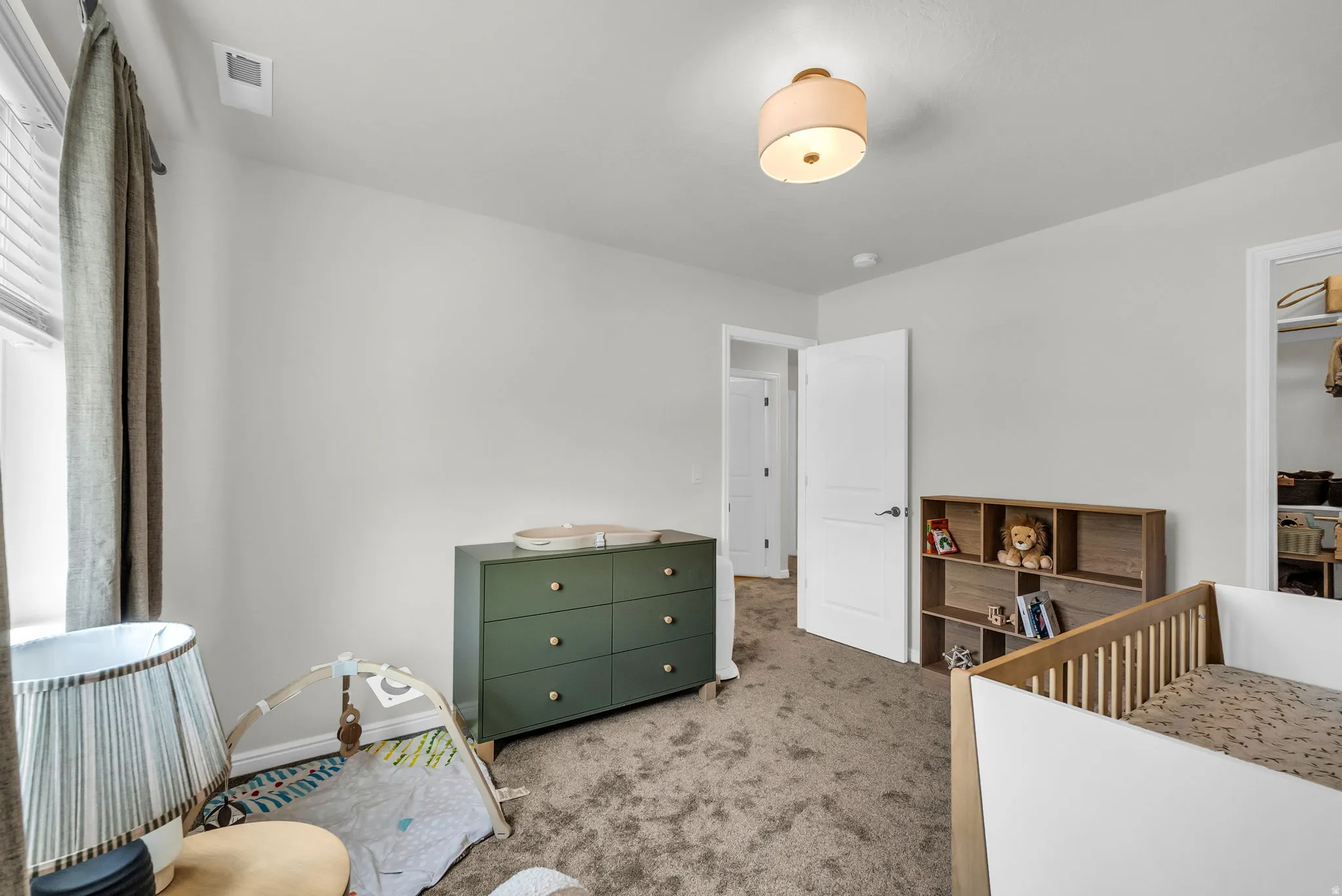 Carpeted room featuring light-toned walls, a window with blinds, and a permanent ceiling light fixture