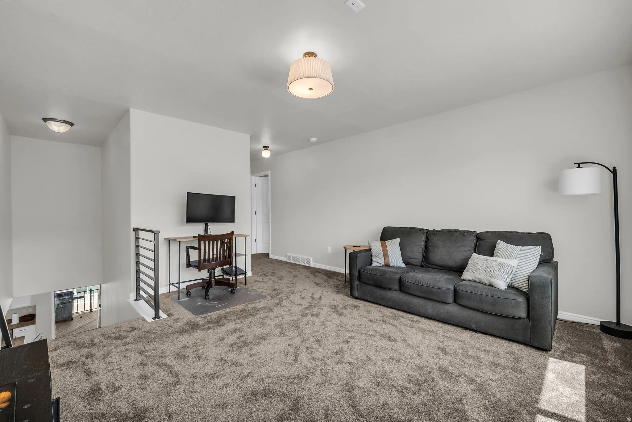 Open loft area featuring gray carpeting and light gray wall paint