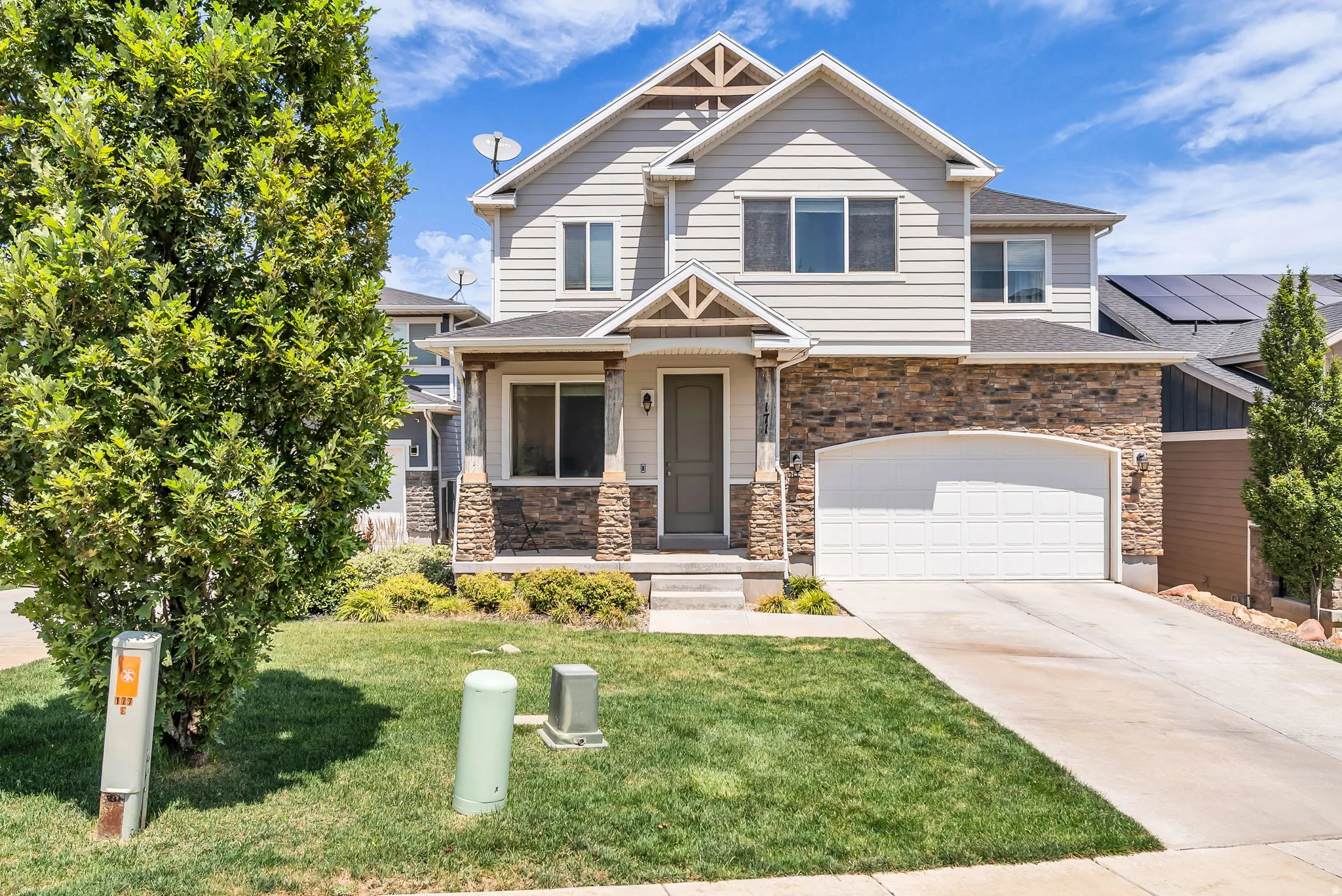 Two-story residence featuring light siding, stone veneer accents, and a covered front entry