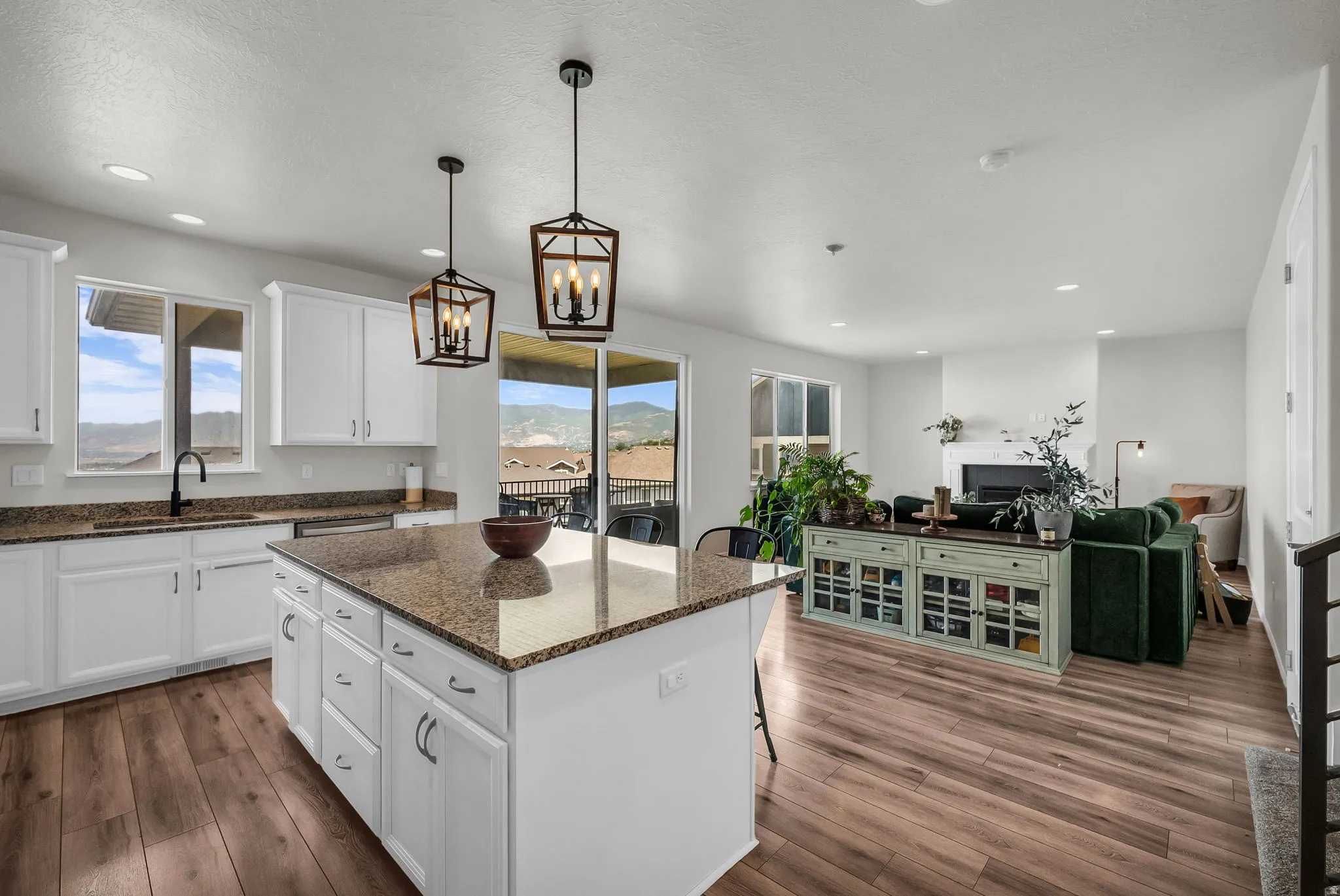 Kitchen island with granite countertop, white cabinetry, wood-finish flooring, recessed lighting, and sliding glass doors leading to a balcony