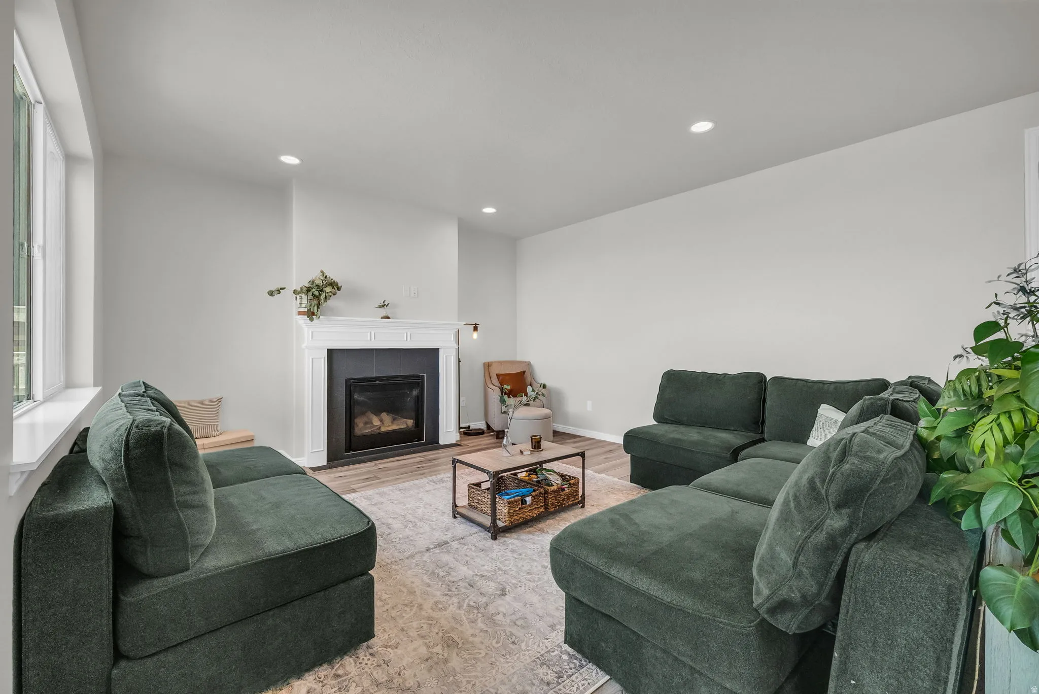 Living space featuring a white mantel fireplace, recessed lighting, large windows, and wood-finish flooring