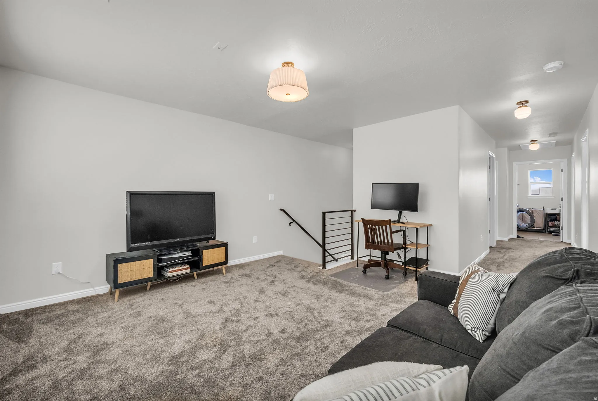 Carpeted recreation room with neutral paint, a contemporary flush mount light fixture, and an open railing staircase
