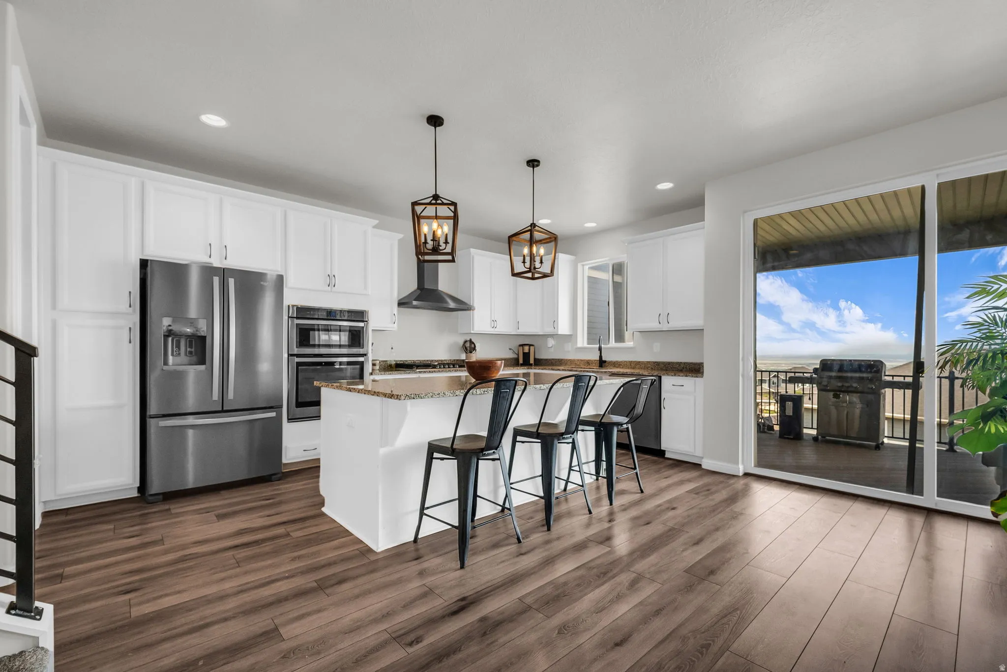 Spacious kitchen featuring white cabinetry, stainless steel appliances, and wood-finish flooring