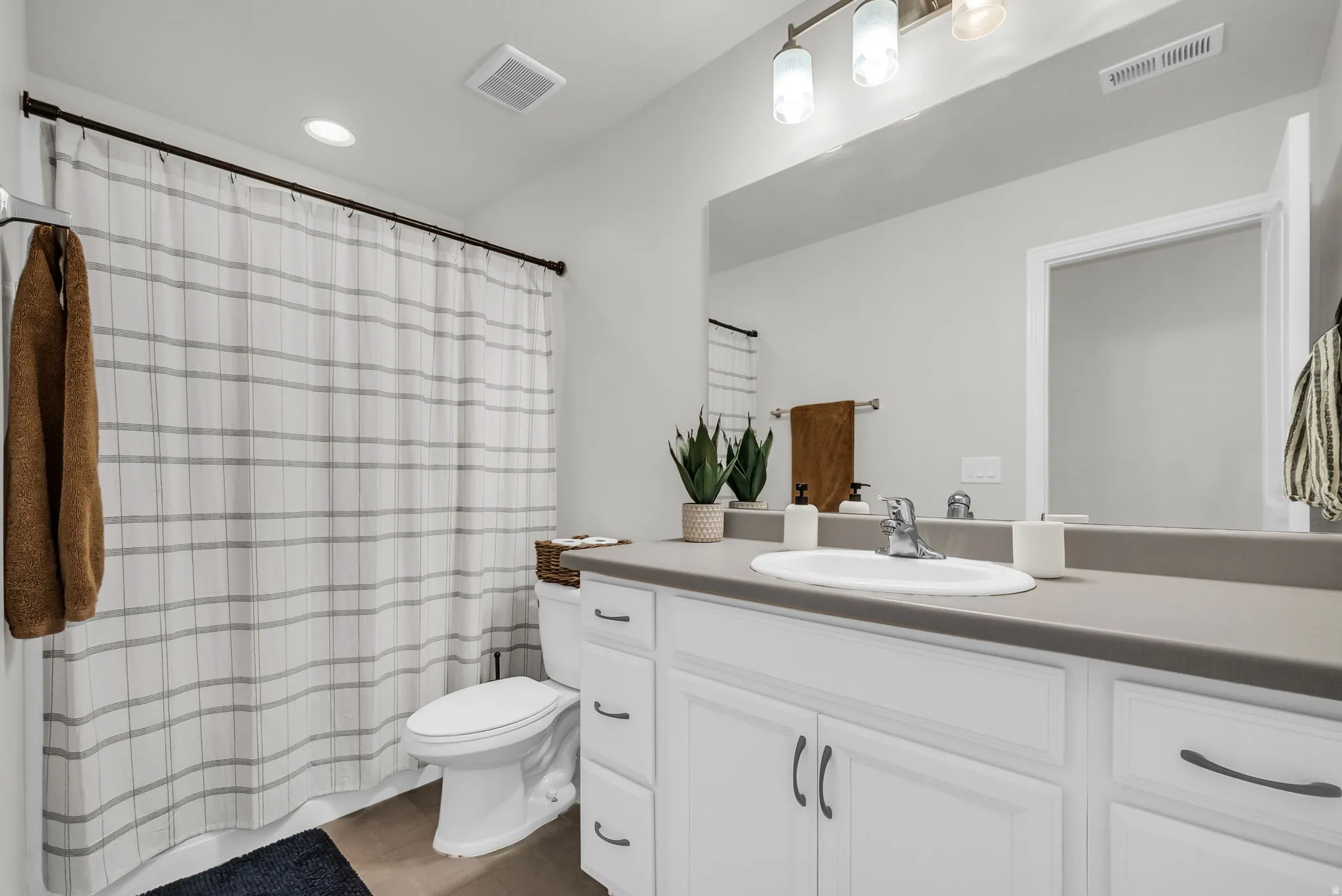 Bathroom featuring a single vanity with white cabinetry, a gray countertop, and an integrated sink