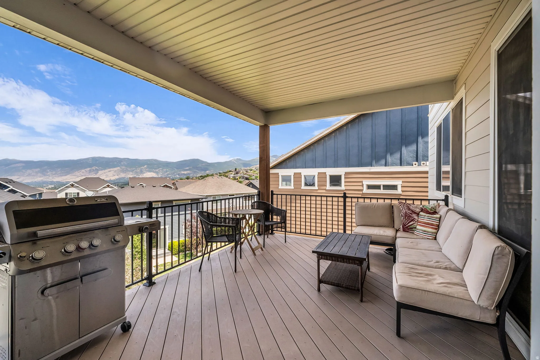 Covered outdoor patio featuring composite decking, a black metal railing, and a tongue-and-groove ceiling
