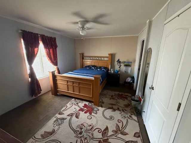 Spacious room featuring a ceiling fan, window with blinds, and white panel doors
